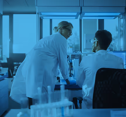 Scientists collaborate in blue-tinted laboratory, working with scientific equipment