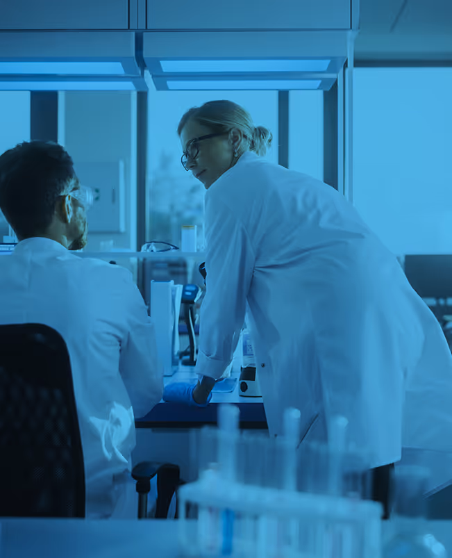 Scientists in white lab coats working together in a blue-tinted laboratory