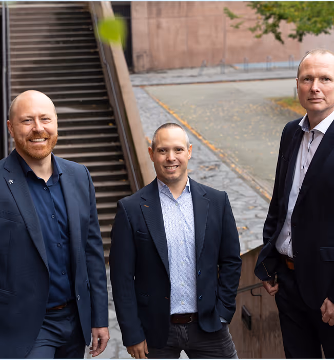 Three businessmen in suits standing together on an outdoor stone staircase