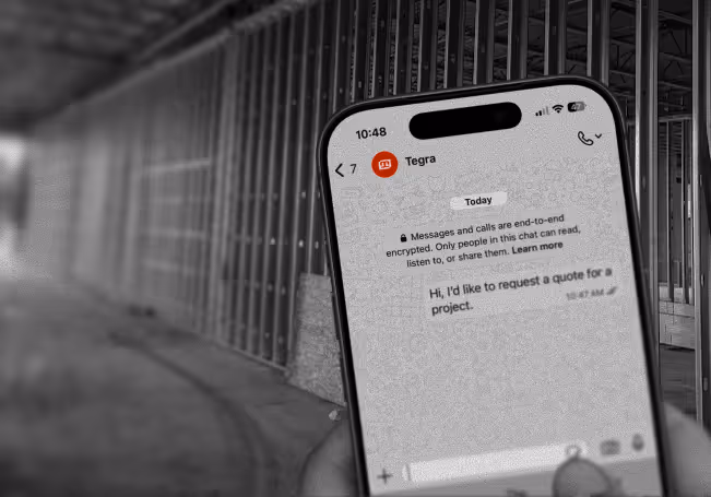 Smartphone held in a hand displaying a WhatsApp chat with a message saying, 'Hi, I'd like to request a quote for a project.'