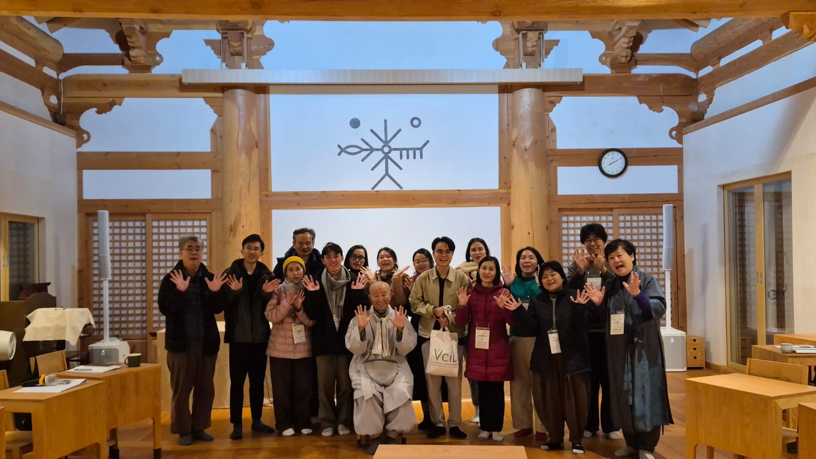 Bốn người phụ nữ đội nón lá và mặc áo phao màu cam đang chèo thuyền trên dòng nước yên bình với cây cối xanh mướt ở ven sông.