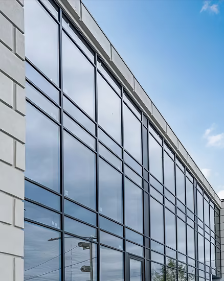 Modern building facade with large reflective glass windows under a clear blue sky.