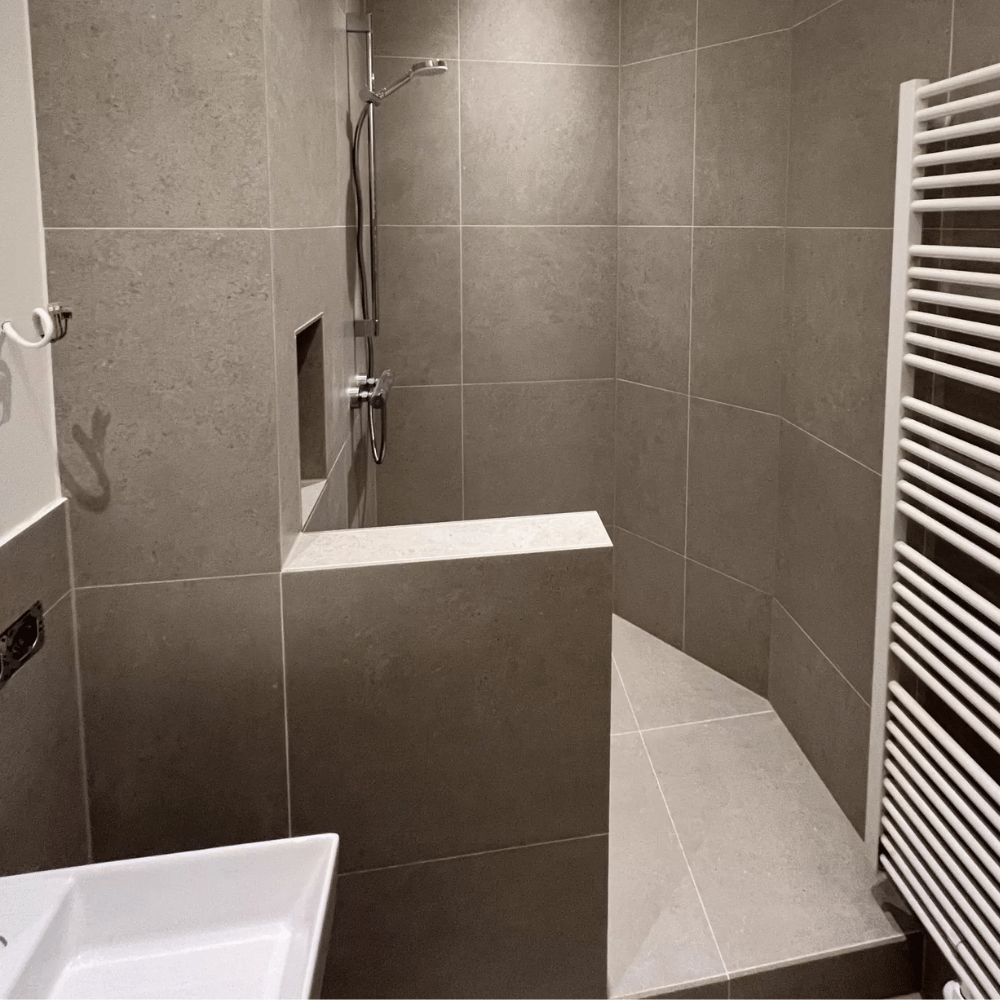 Badezimmer mit bodengleicher Dusche und dunklen Wandfliesen in Hamburg