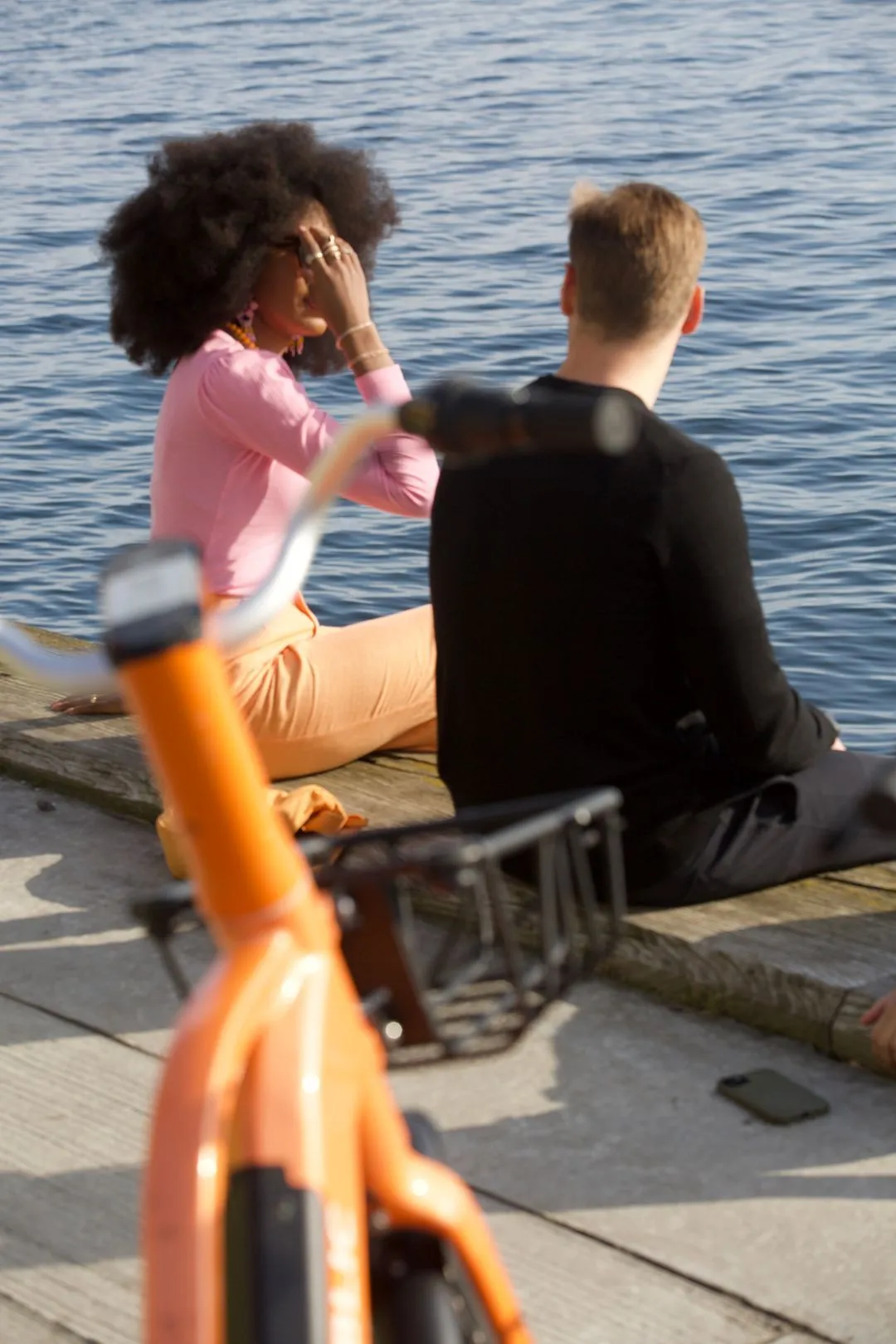 Couple sitting near waterbody with bikes