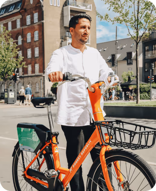 A man standing next to a bike on a city street.