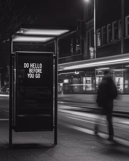 Black and white nighttime urban scene with a bus stop sign reading 'DO HELLO BEFORE YOU GO' and a blurred figure walking near a moving tram.