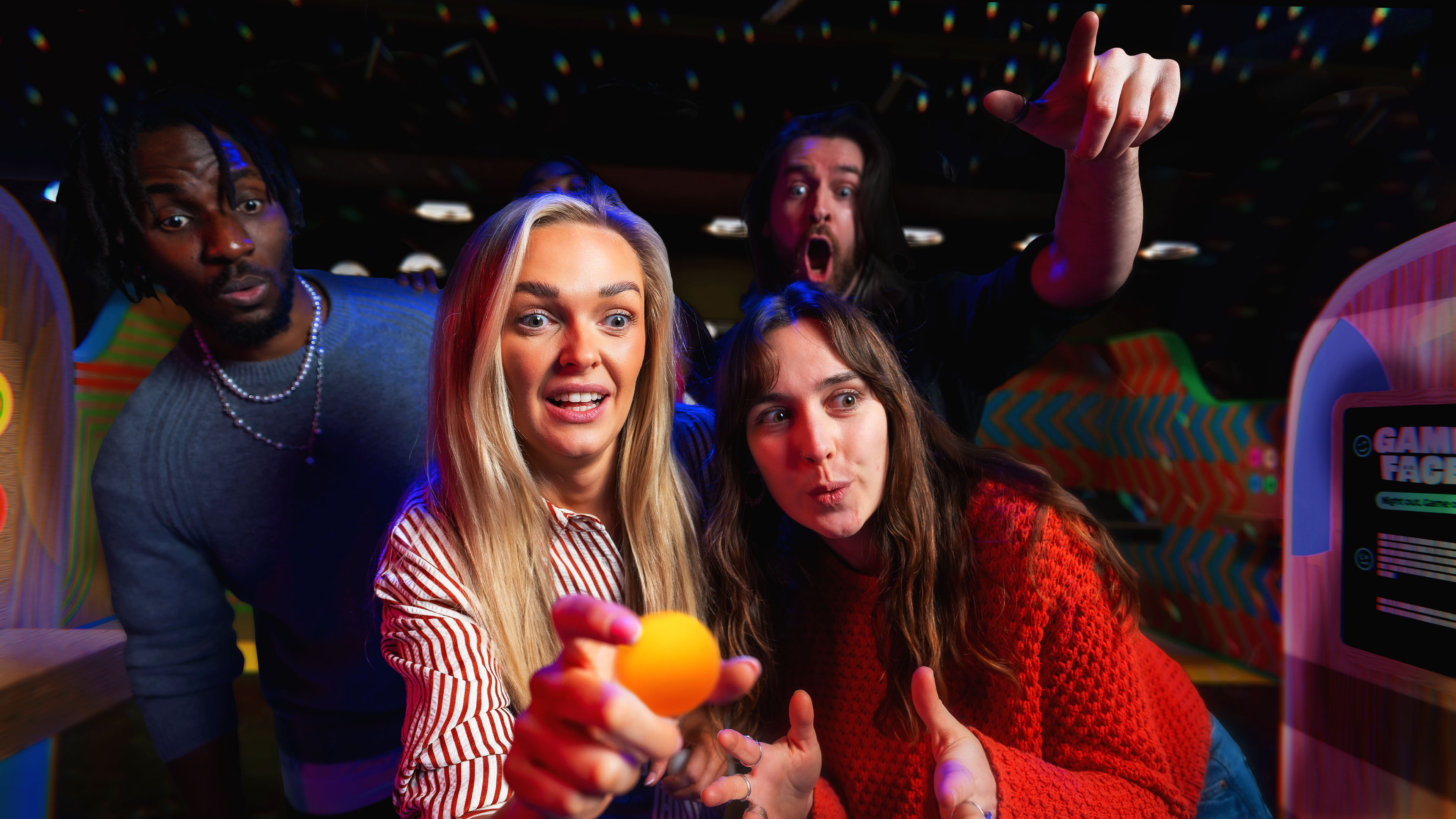 Three friends lying on the floor surrounded by confetti, smiling and taking a selfie together.
