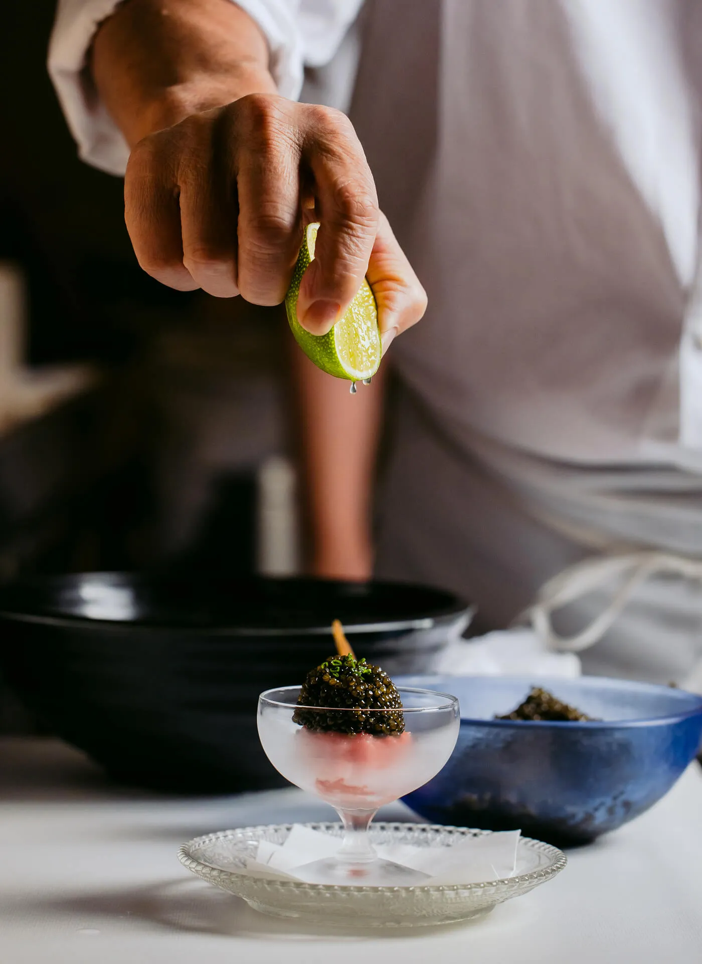 Step 3/3 of a Chef carefully preparing Masa Toro Tartare Caviar, squeezing lime.
