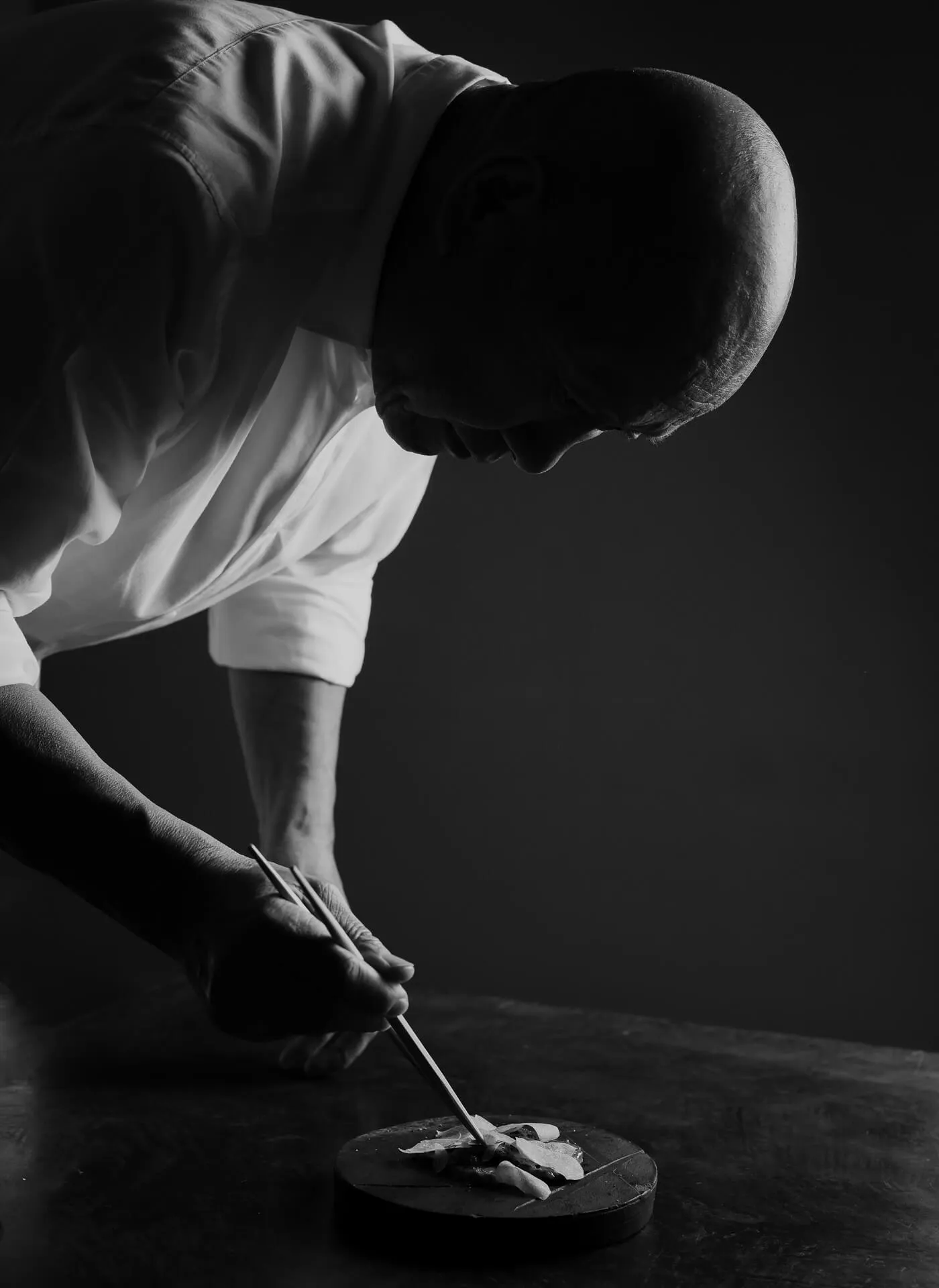 A zoomed out view of Chef masa plating a dish using Chopsticks