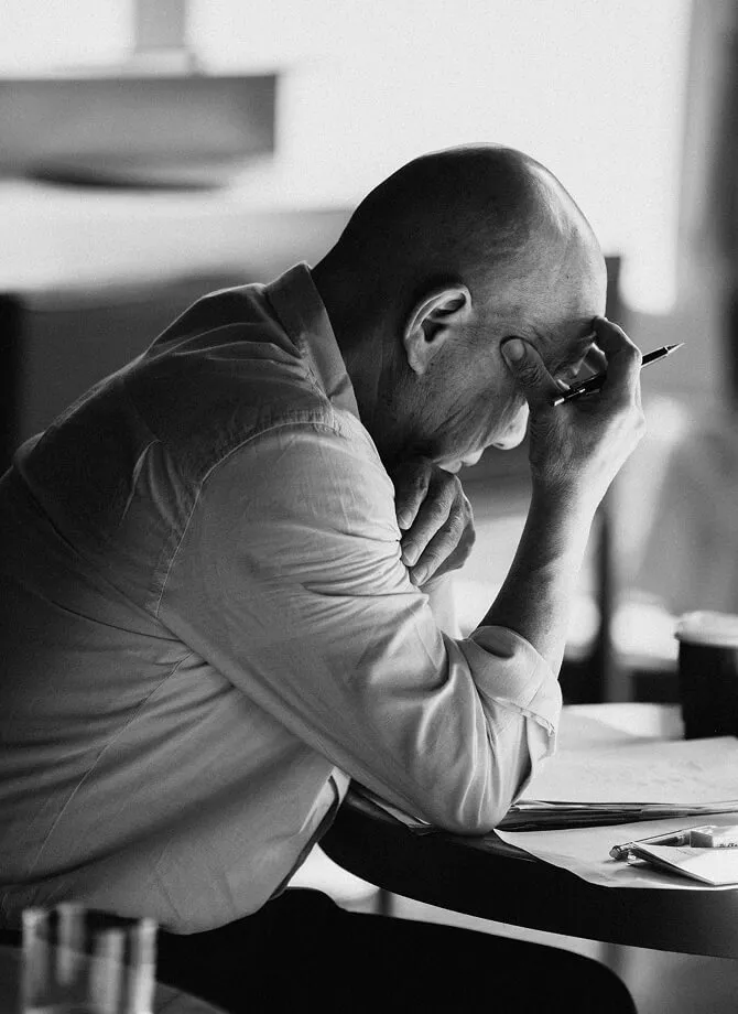 Chef masa working on something at a table, holding a pencil