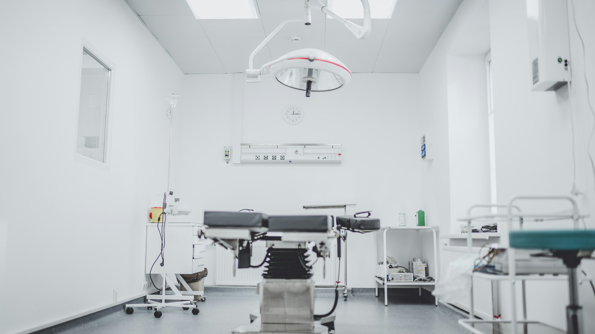 Empty modern surgical operating room with an operating table, overhead surgical light, and medical equipment.