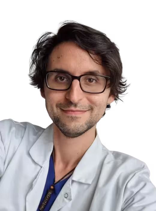 Middle-aged man with light beard and short hair wearing a white button-up shirt, standing outdoors with green foliage background.