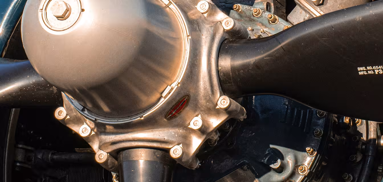Close-up of a black aircraft propeller attached to a silver metallic engine hub with bolts.