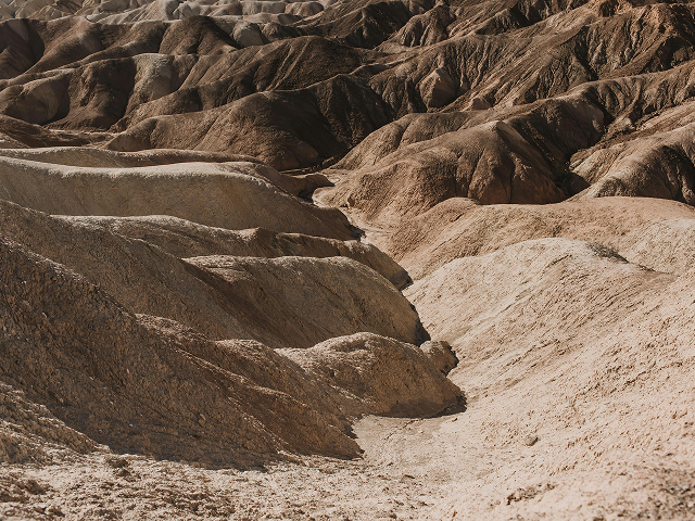Arid desert landscape with rugged, eroded brown and tan hills.