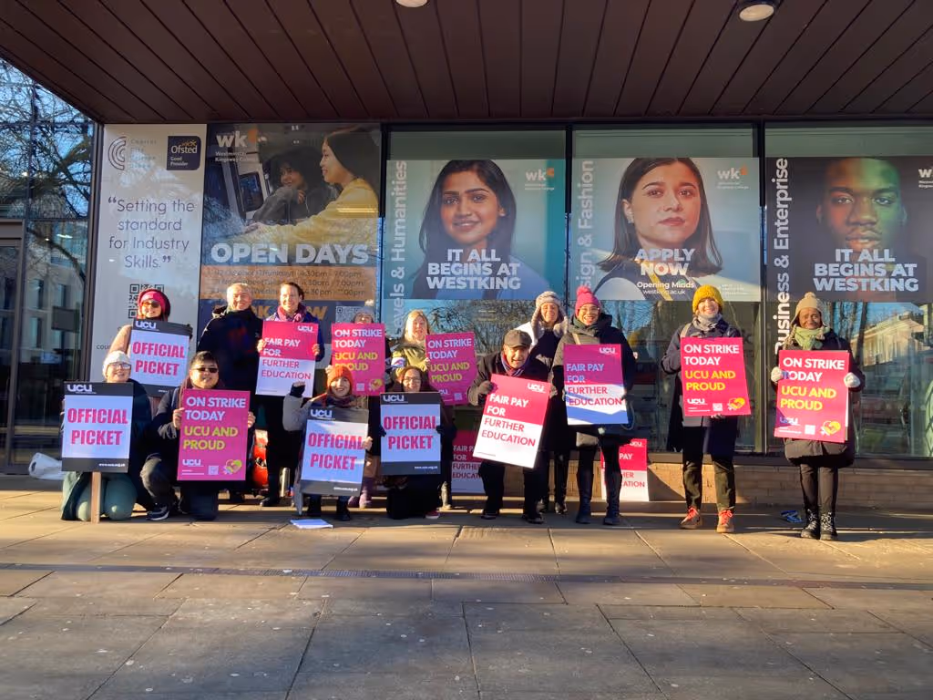 Group of people holding protest signs outside a building with large posters promoting Westking, advocating for fair pay and education on strike.