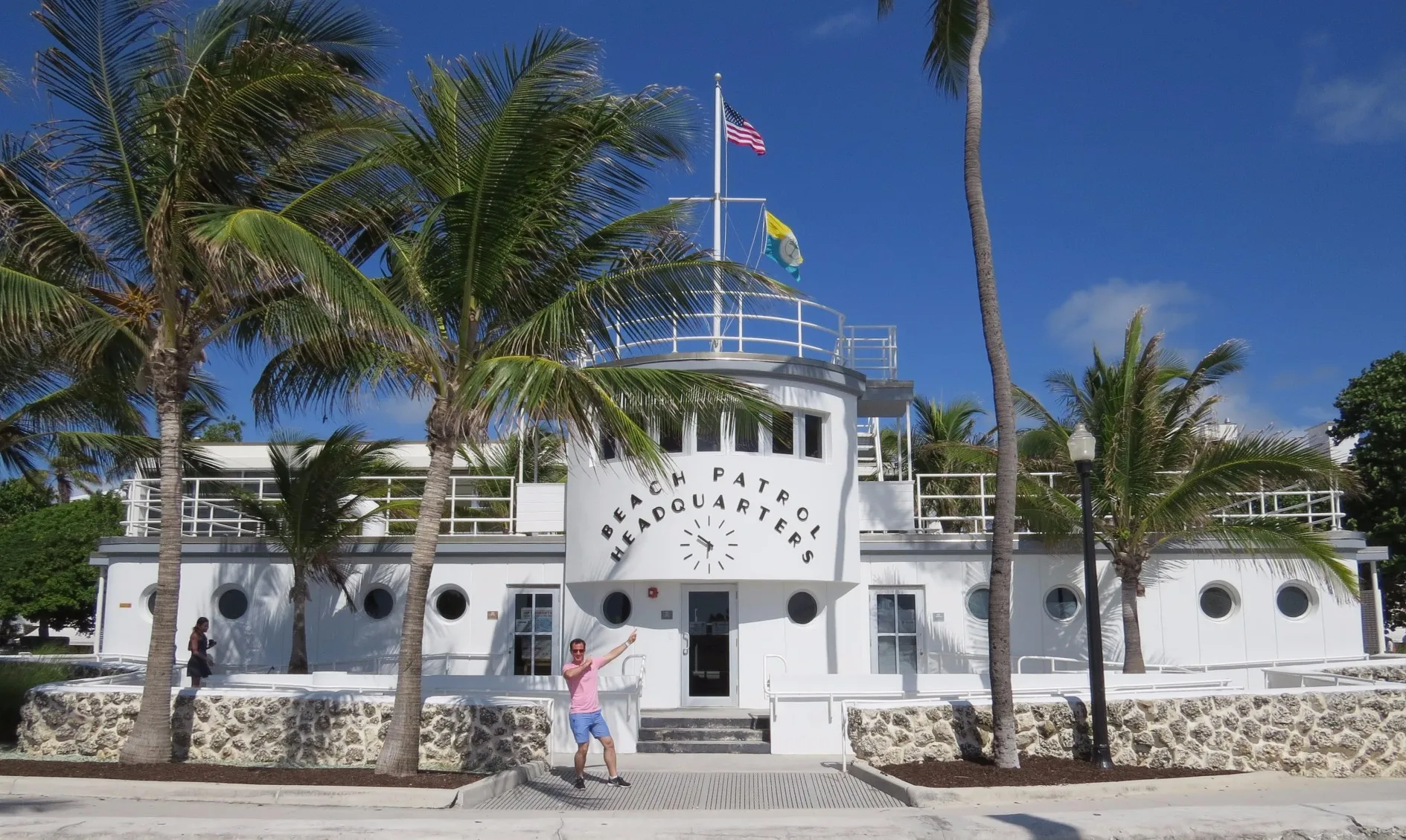 White Beach Patrol Headquarters building with American flag on top, surrounded by palm trees and clear blue sky.