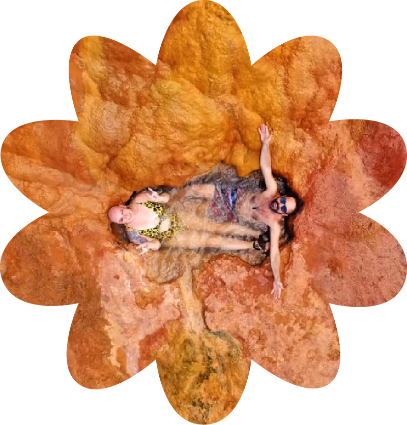 A photo of Abby and Wade in the middle of a canyon pool, shot from above, it looks unreal. The natural colors of the stone are incredible.