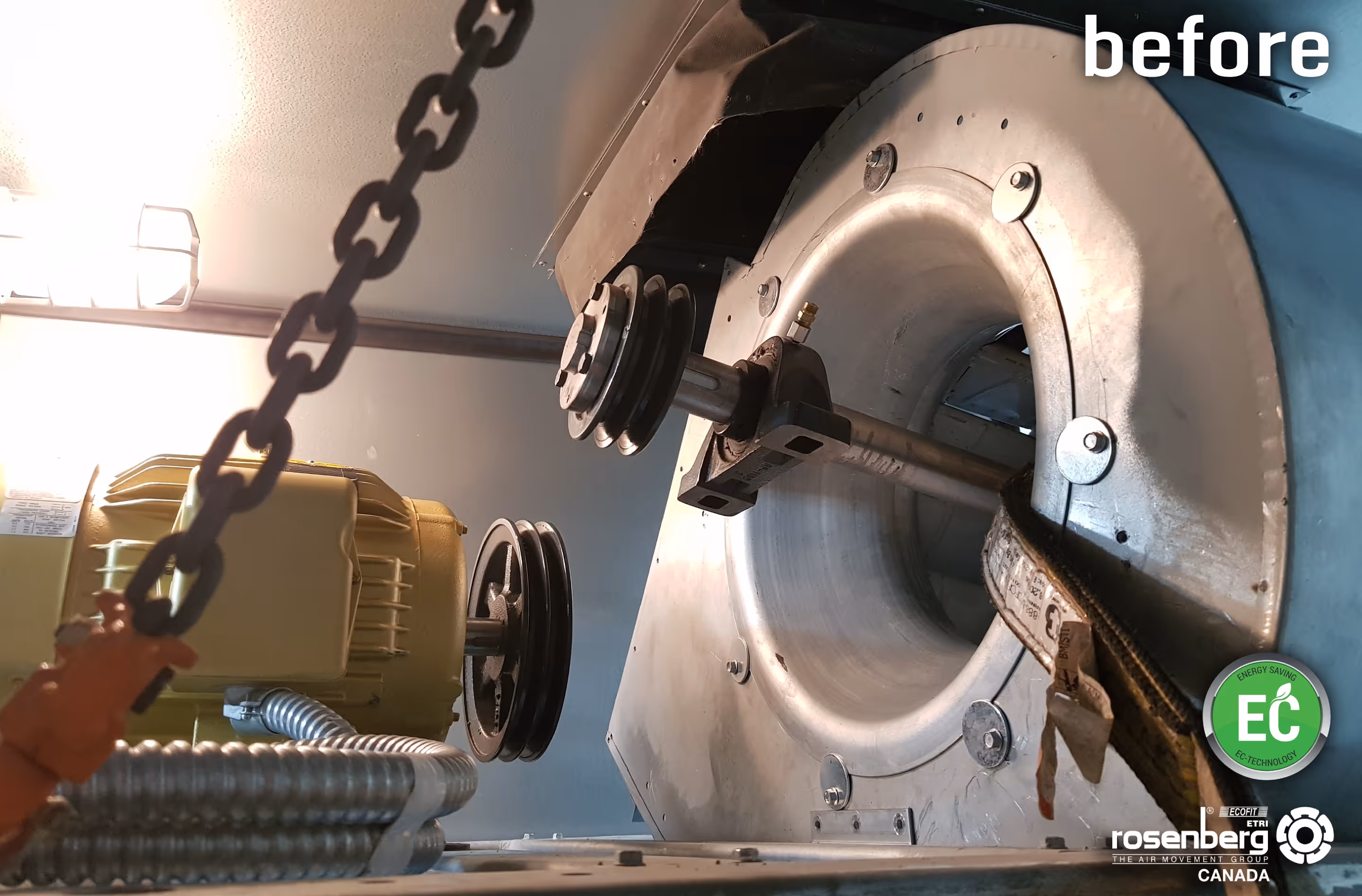 Metal fan housing with pulleys attached to a motor inside an industrial ventilation system.