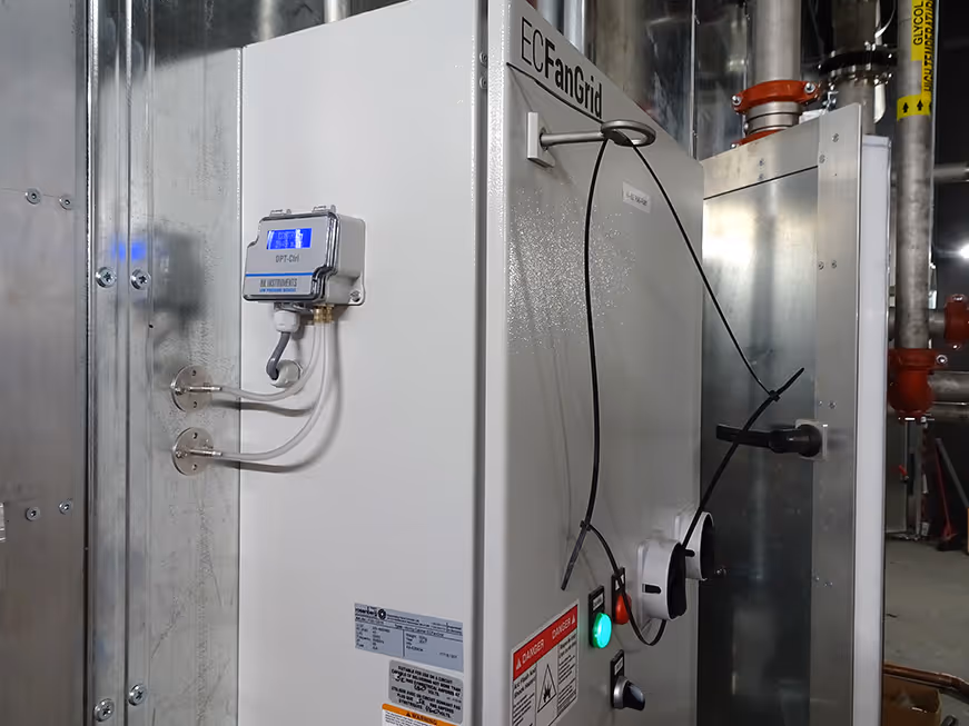Industrial white EC Fan Grid air handling unit with control box and warning labels in mechanical room.