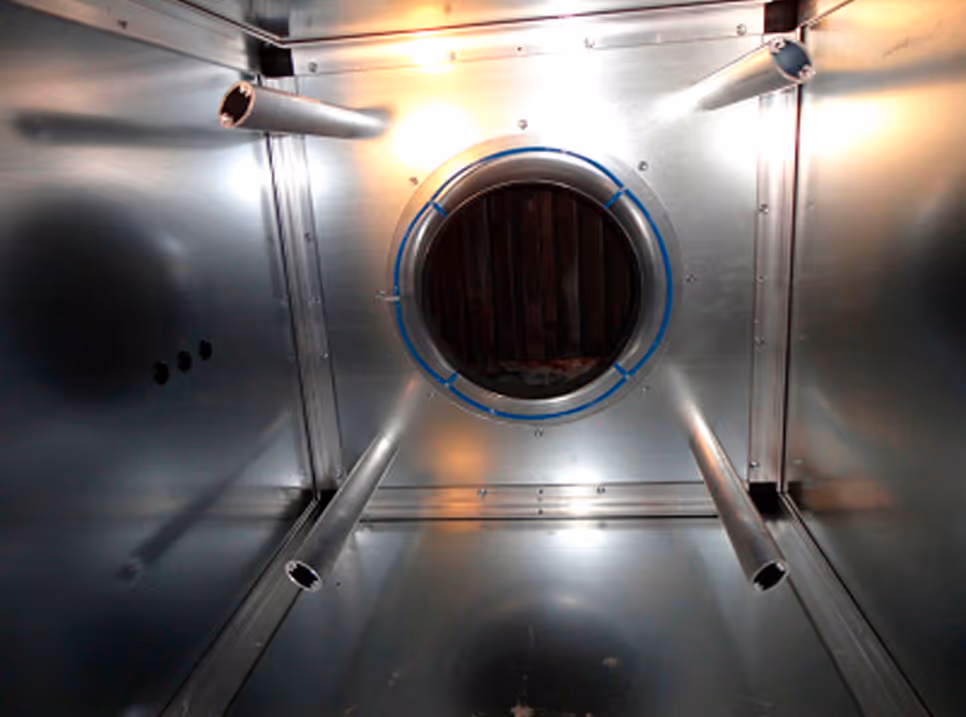 Inside view of a metallic ventilation duct with circular openings and cylindrical extensions.