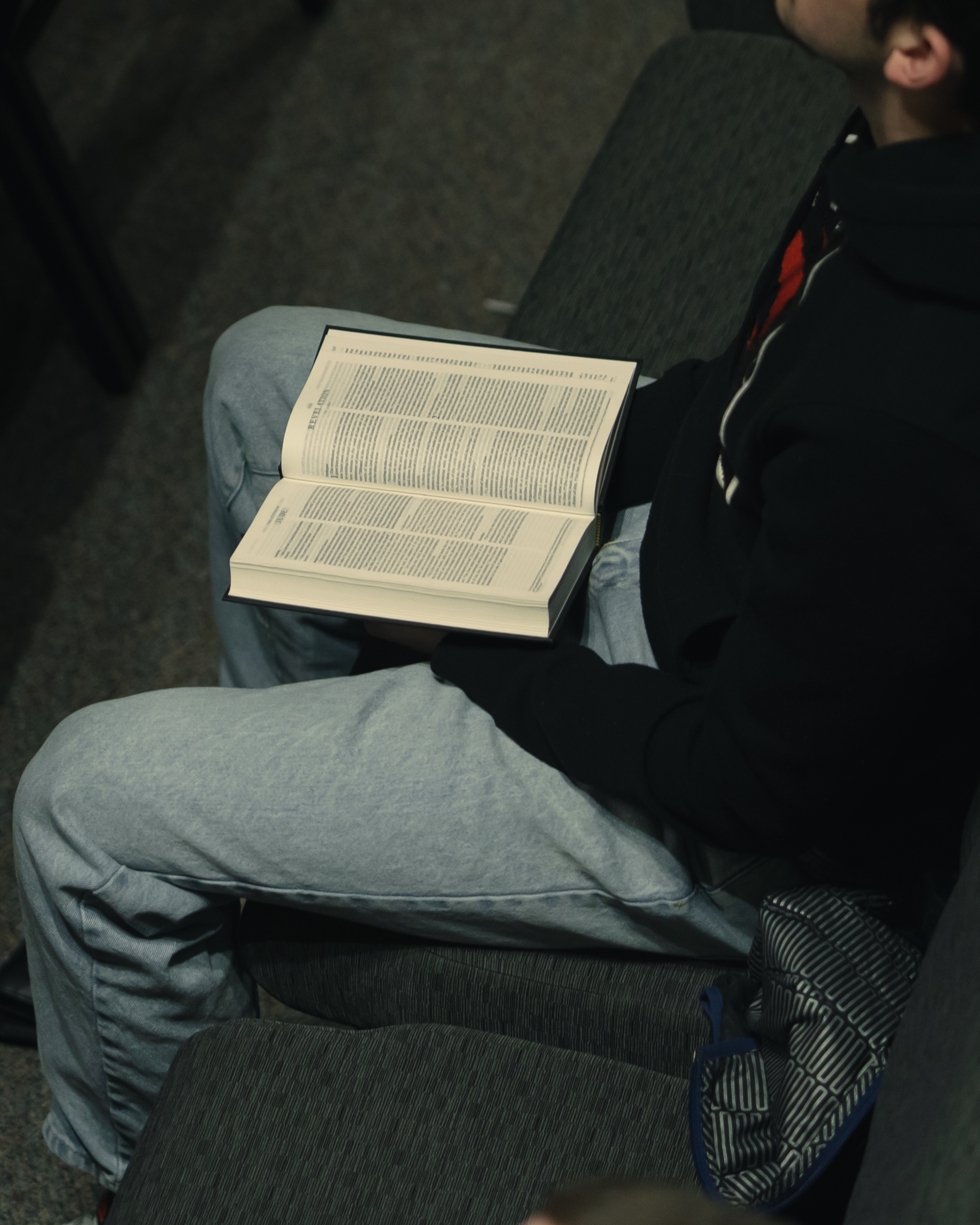 Toddler boy holding hands with a younger toddler girl inside a room, both seen from behind.