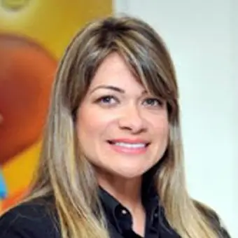 Andrea Silva sorridente com longos cabelos loiros, vestindo uma camisa preta, em frente a um fundo colorido.