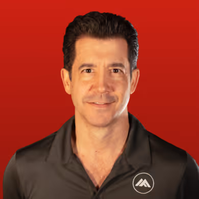 Man with dark hair wearing a black polo shirt with a mountain-shaped logo on a red background.