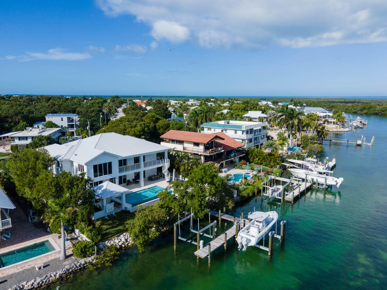 Aerial view of waterfront homes with private docks and boats on a clear sunny day.