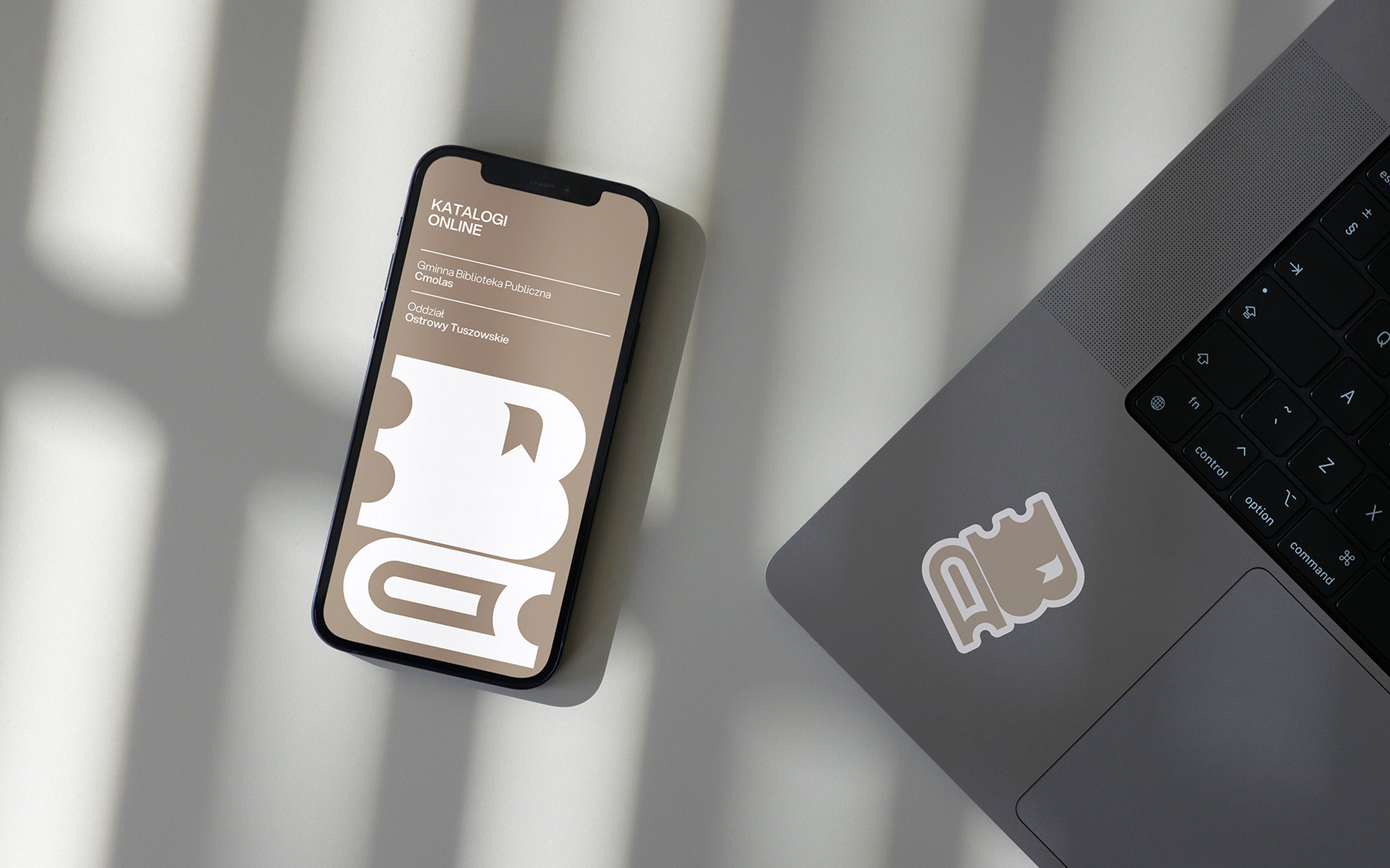 Logo dla biblioteki w formie naklejki na laptopie oraz logo biblioteki użyte jako grafika strony internetowej - wersja mobilna