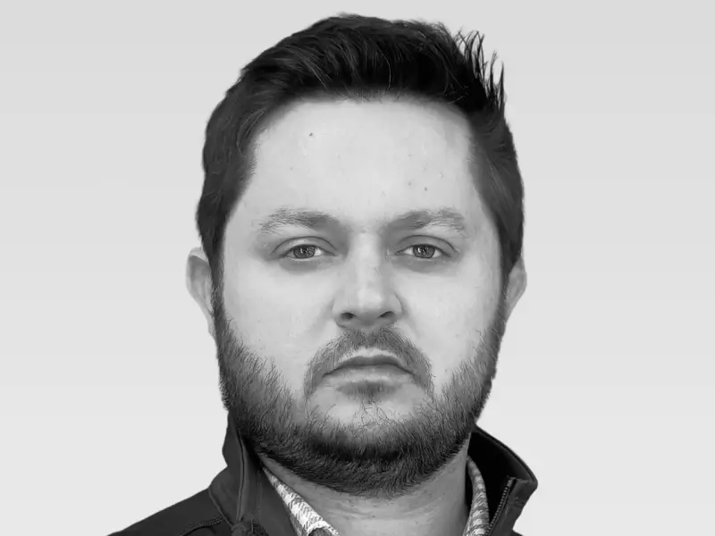 Black and white headshot of a woman with long straight hair, wearing a single dangling earring and a blazer, smiling slightly.