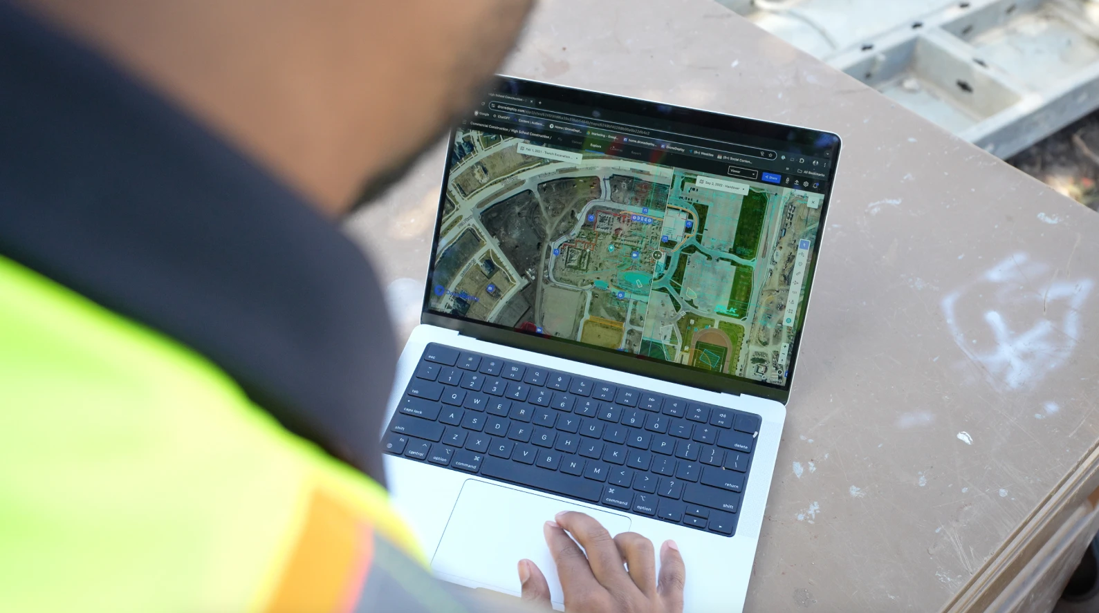 Over the shoulder of someone using dronedeploy on a laptop on site
