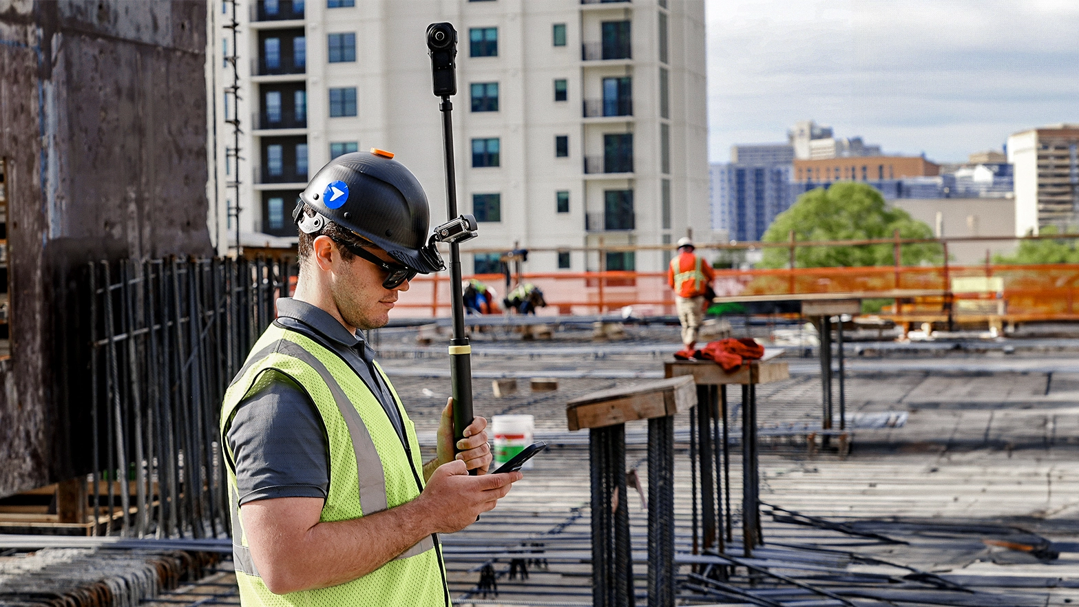 A construction worker using a 3D camera and his smartphone.