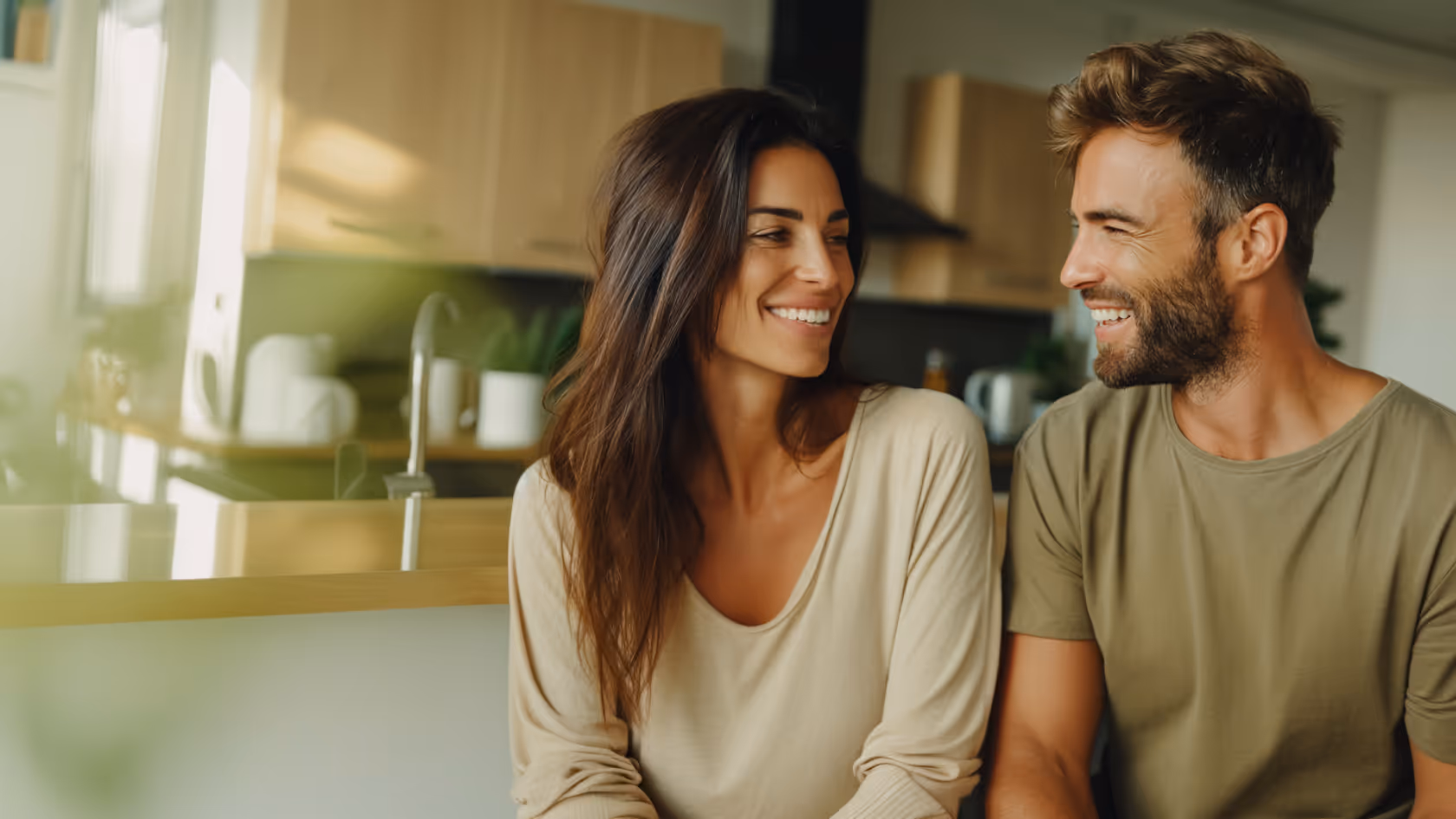 Smiling middle-aged couple standing outdoors near a lakeside cabin at dusk.