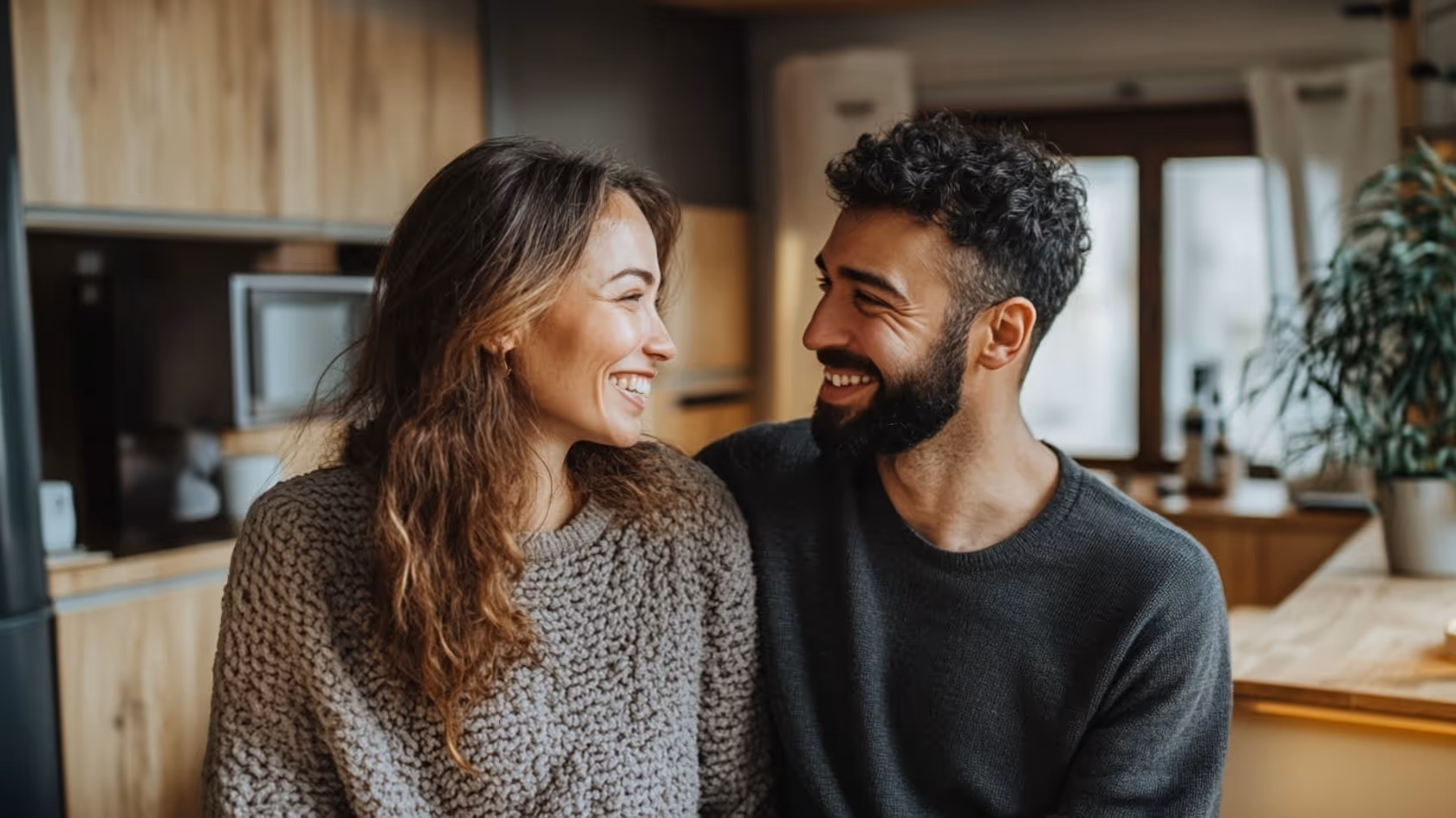 Smiling couple relaxing together on a couch in a warmly lit room.