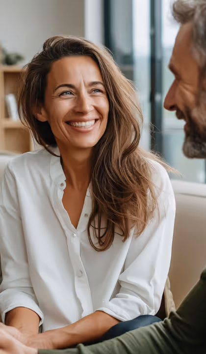 Smiling mature couple looking at each other outdoors during sunset.