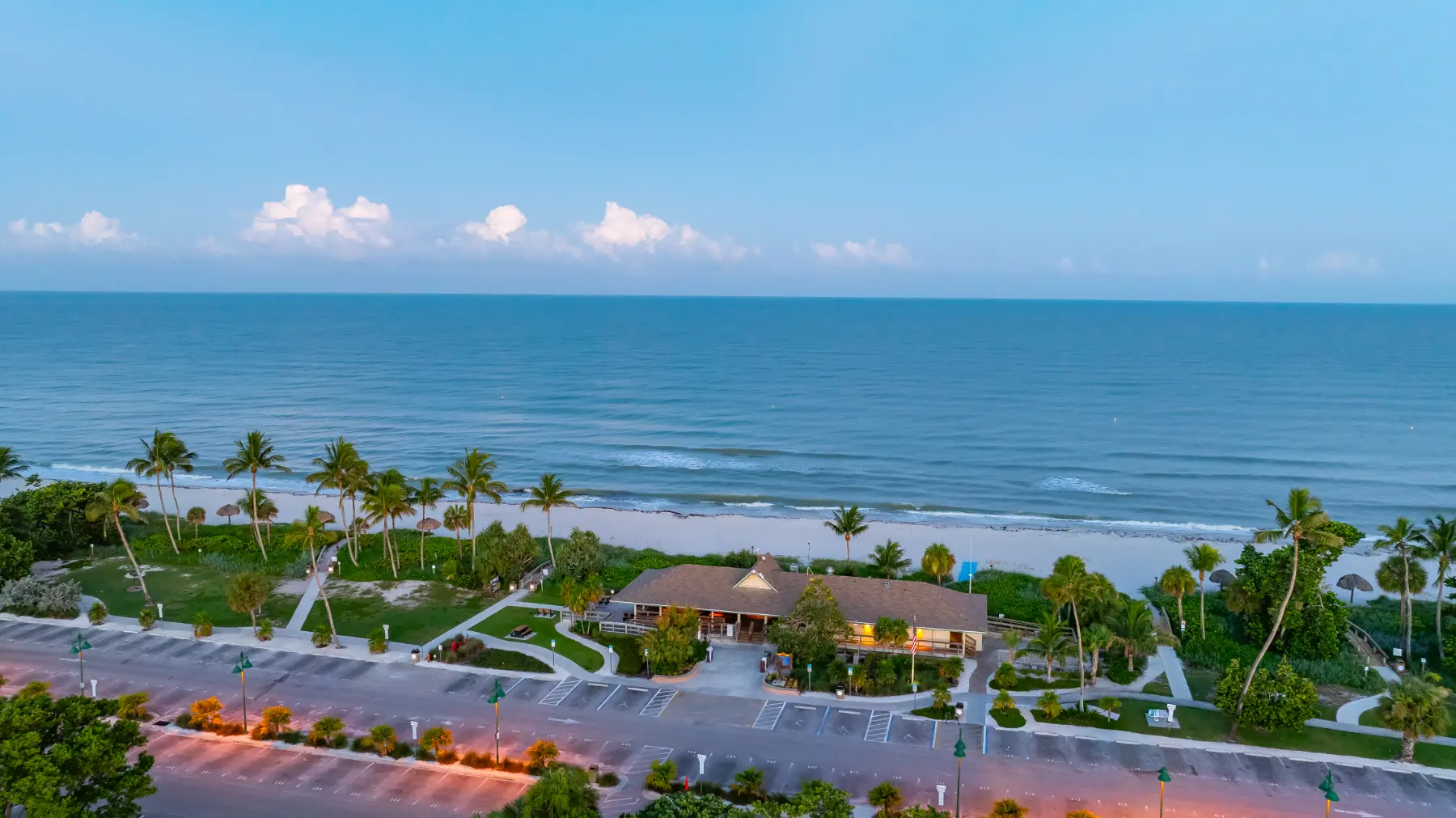 Beachfront buildings along Gulf Shore Blvd with waves and a sunset sky in the background.