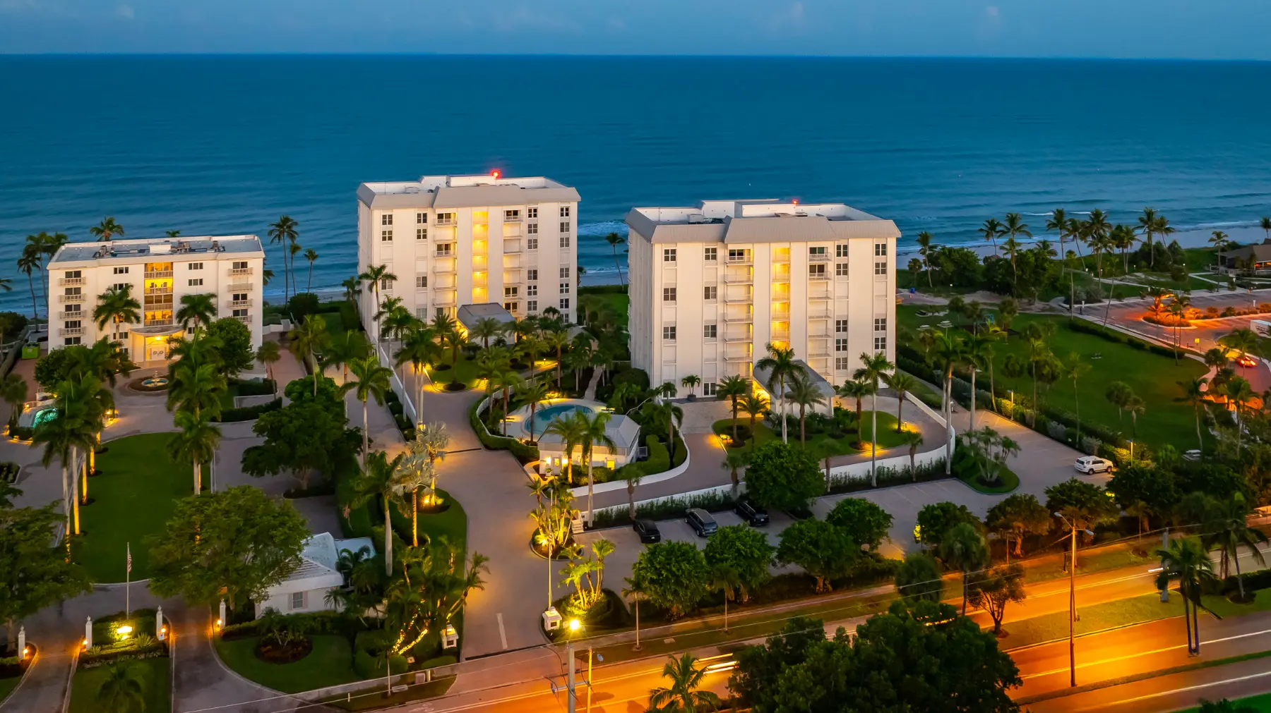 Aerial view of beachfront buildings along a white sandy beach with clear turquoise ocean water along Gulf Shore Blvd N.
