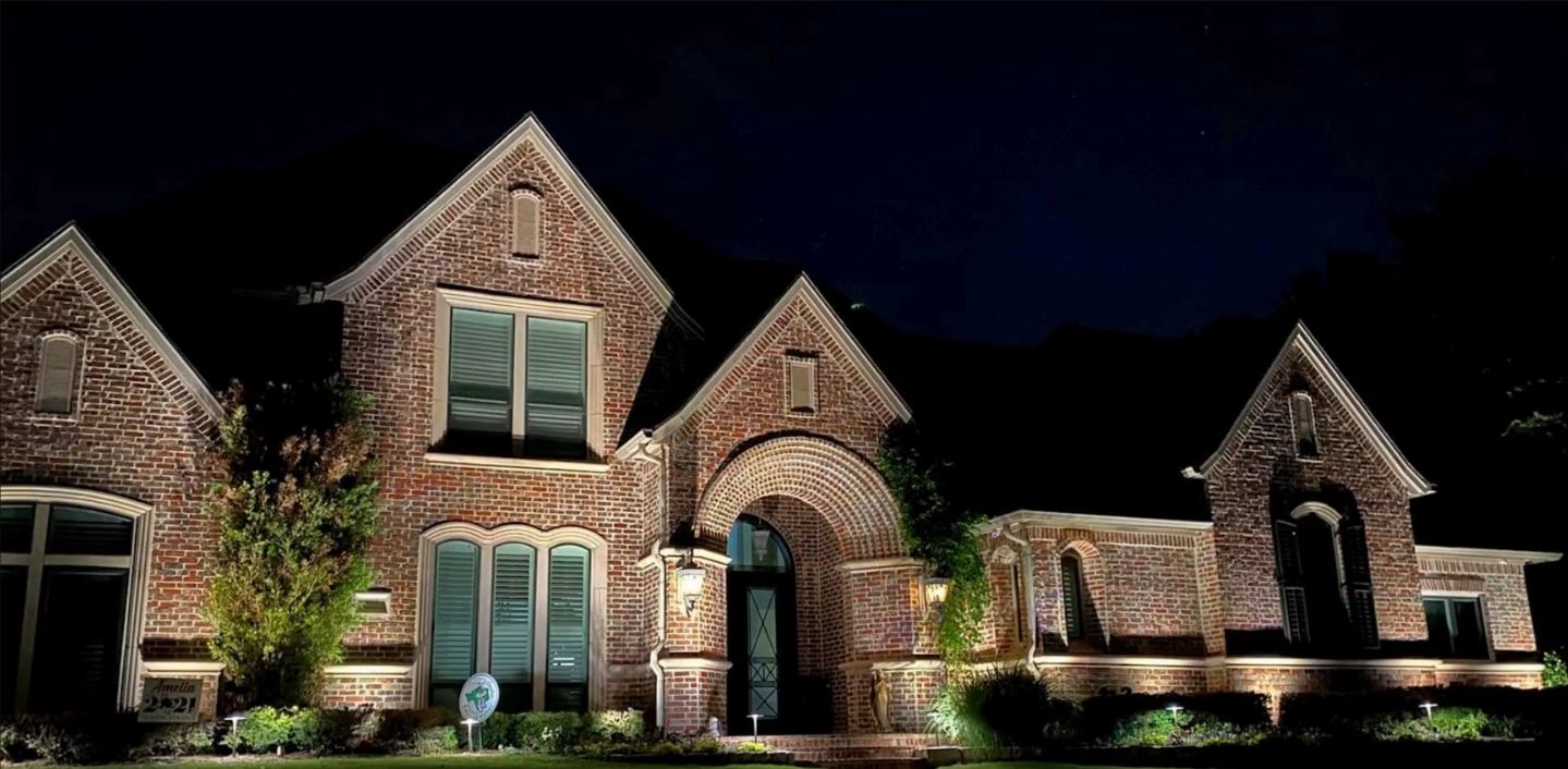 Large brick house illuminated at night with arched doorway and multiple windows.