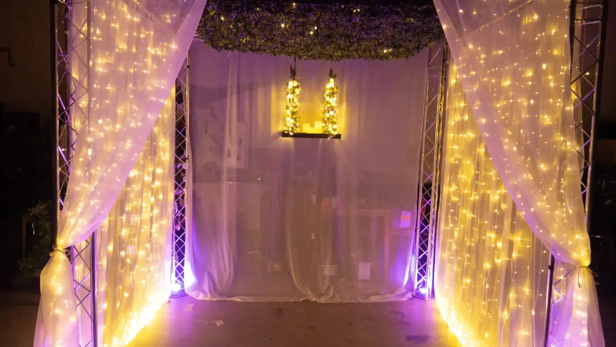 Curtain backdrop with warm fairy lights and hanging lights, framed by white sheer drapes.