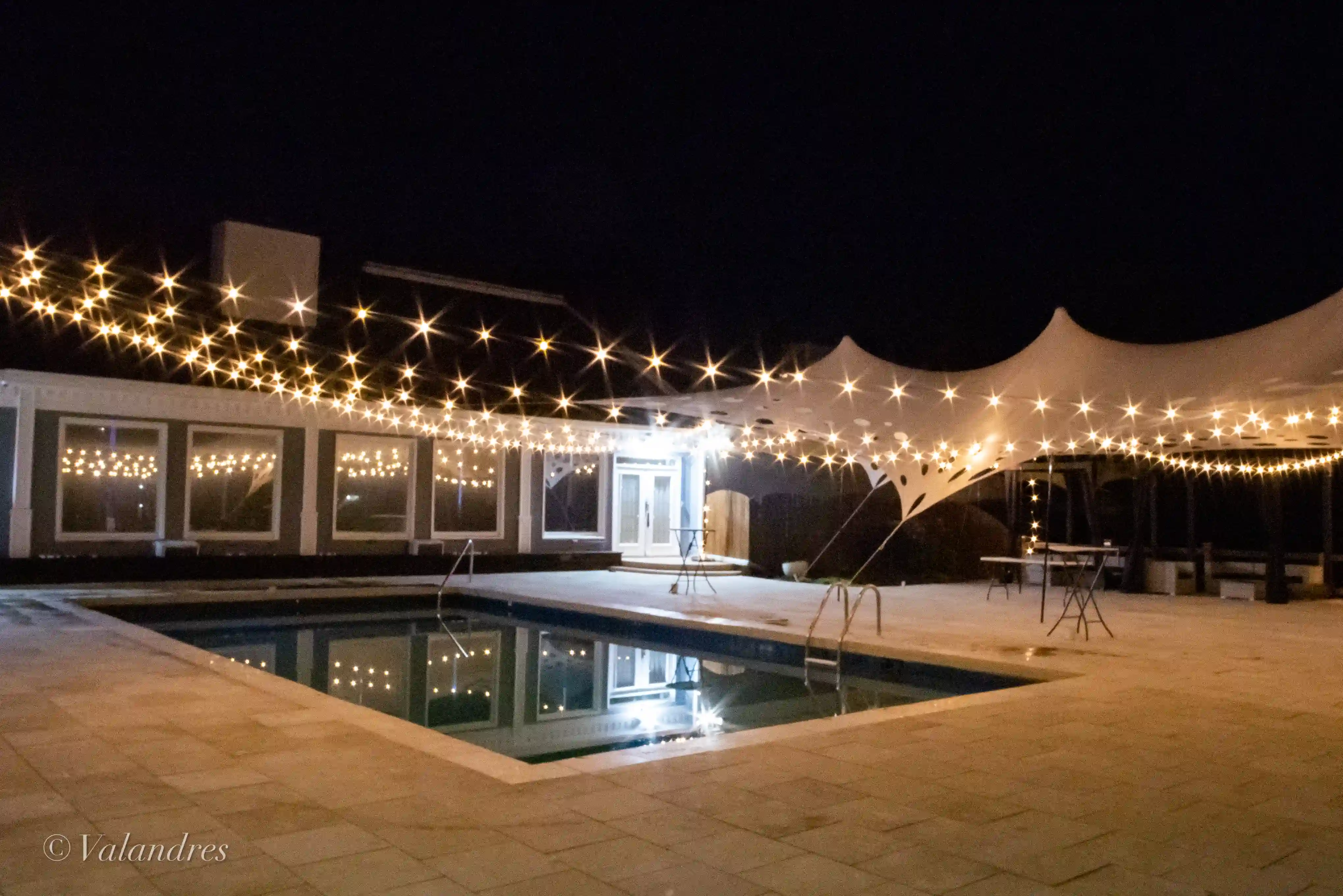 Warm outdoor lighting installation on a residential home exterior at dusk, featuring glowing LED lights that enhance landscaping and architectural elements. The professional lighting design creates a welcoming atmosphere and highlights outdoor spaces for enhanced curb appeal.