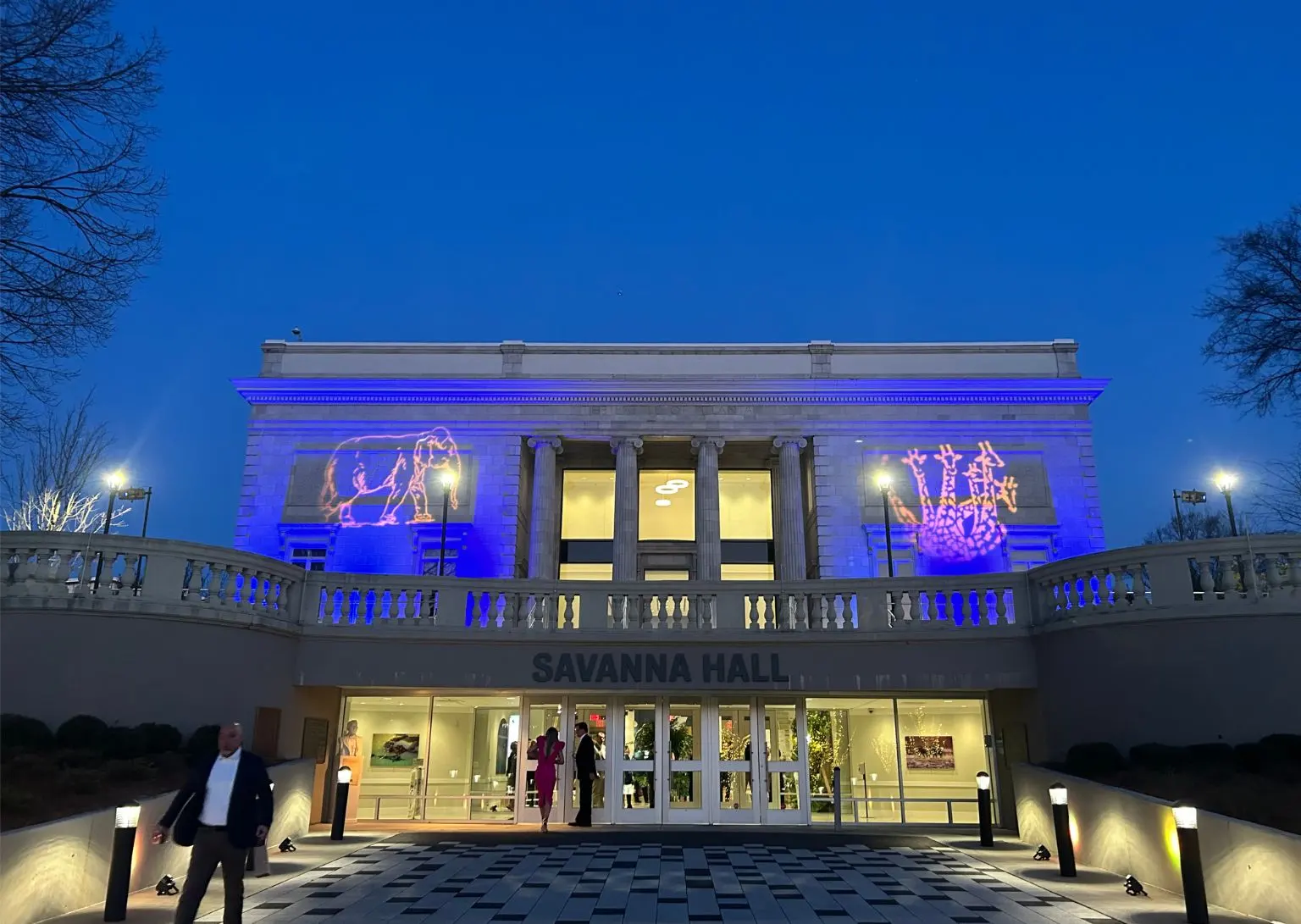 Savanna Hall at night with blue lighting and animal projections of a lion and giraffes on the facade.