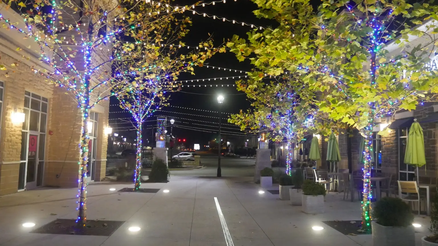 Commercial brick building at night featuring custom purple roofline string lighting and illuminated storefront.
