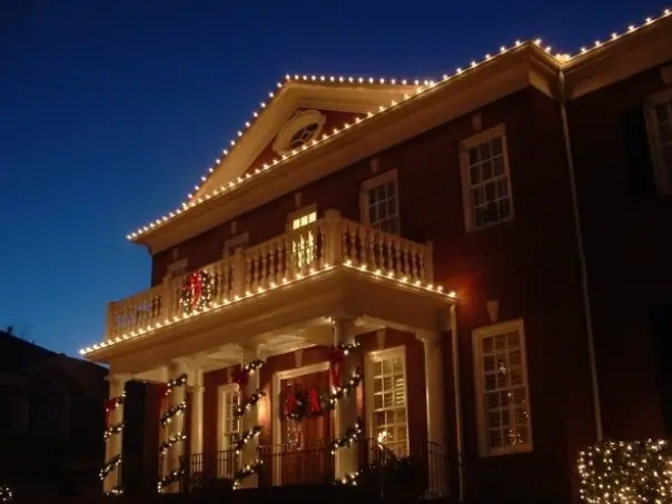 Outdoor event lighting setup featuring string lights creating a vibrant atmosphere for a gathering. The scene shows people enjoying the event in a well-lit space, highlighting the transformative effect of custom lighting solutions for parties, celebrations, and social events.