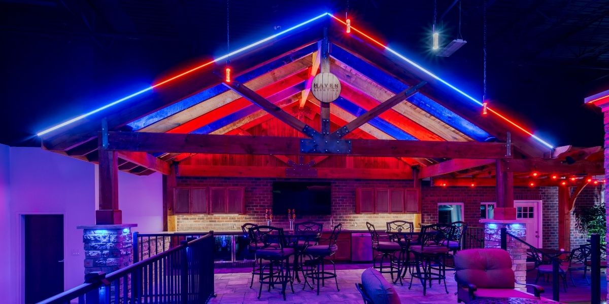 Modern outdoor patio illuminated with colorful LED architectural lighting, showcasing professional uplighting design for events, entertainment spaces, and permanent exterior lighting installations.