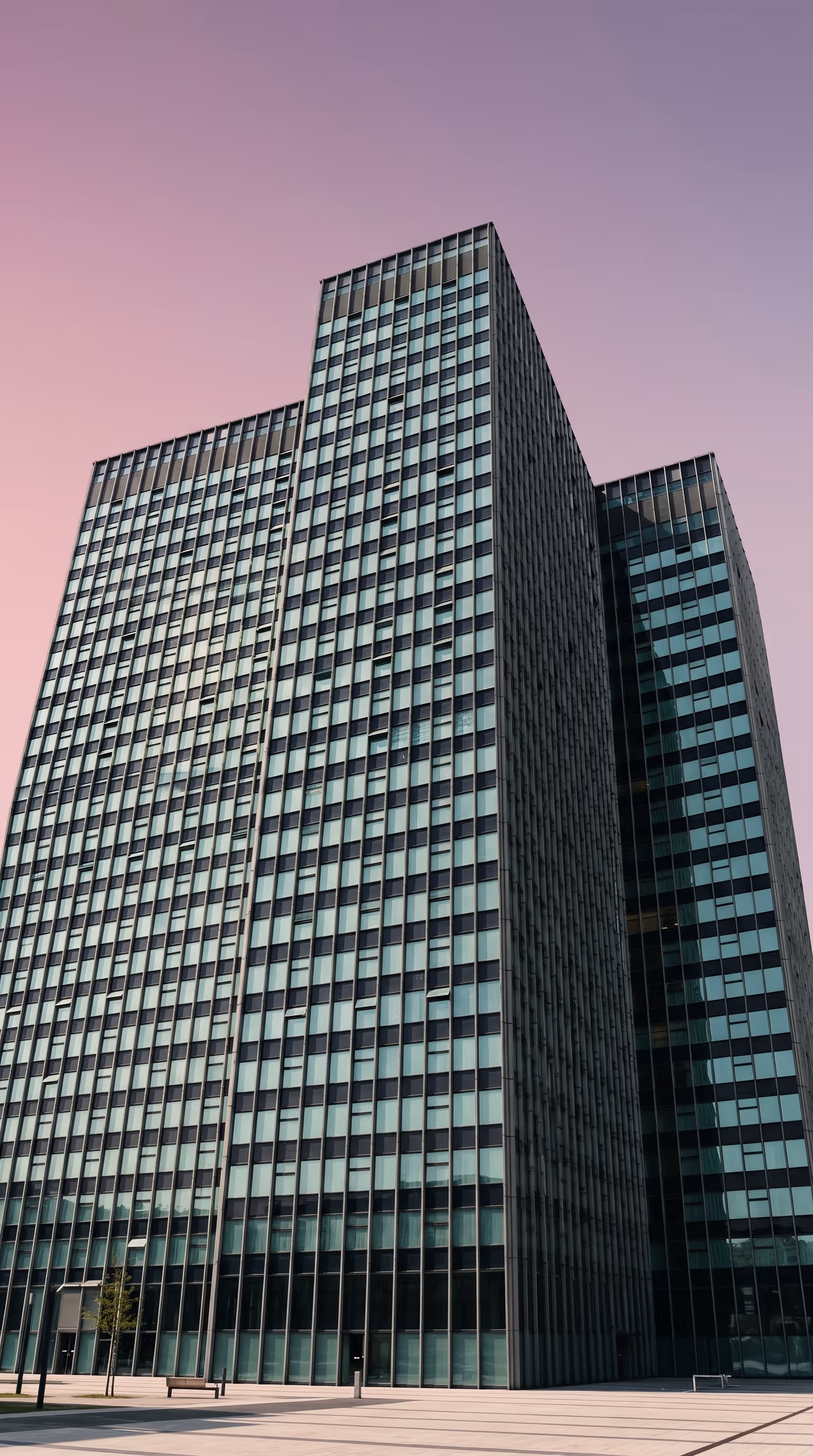 Modern glass office tower photographed from ground level against a dusky sky, representing West Country Energy Services headquarters in Red Deer, Alberta, a Canadian field services company providing vegetation management, pipeline integrity, and emissions management across Alberta and Saskatchewan.