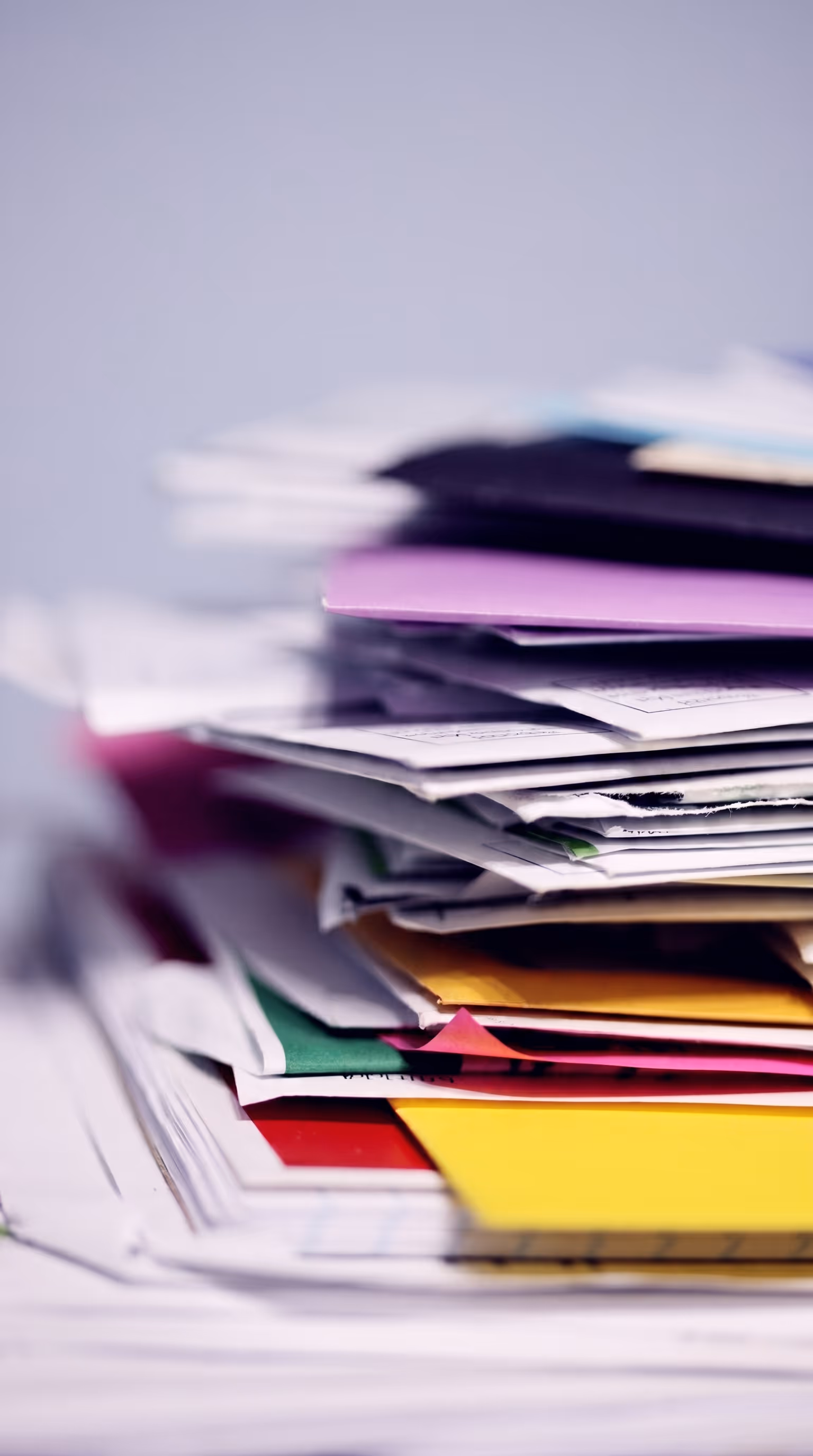 A tall disorganized stack of colourful paper documents, folders, and forms, representing the fragmented spreadsheet and manual field data management challenge NorthWind Land Resources faced before Matidor, including over 15 field form types, scattered project information, and no centralized platform accessible to the full team.