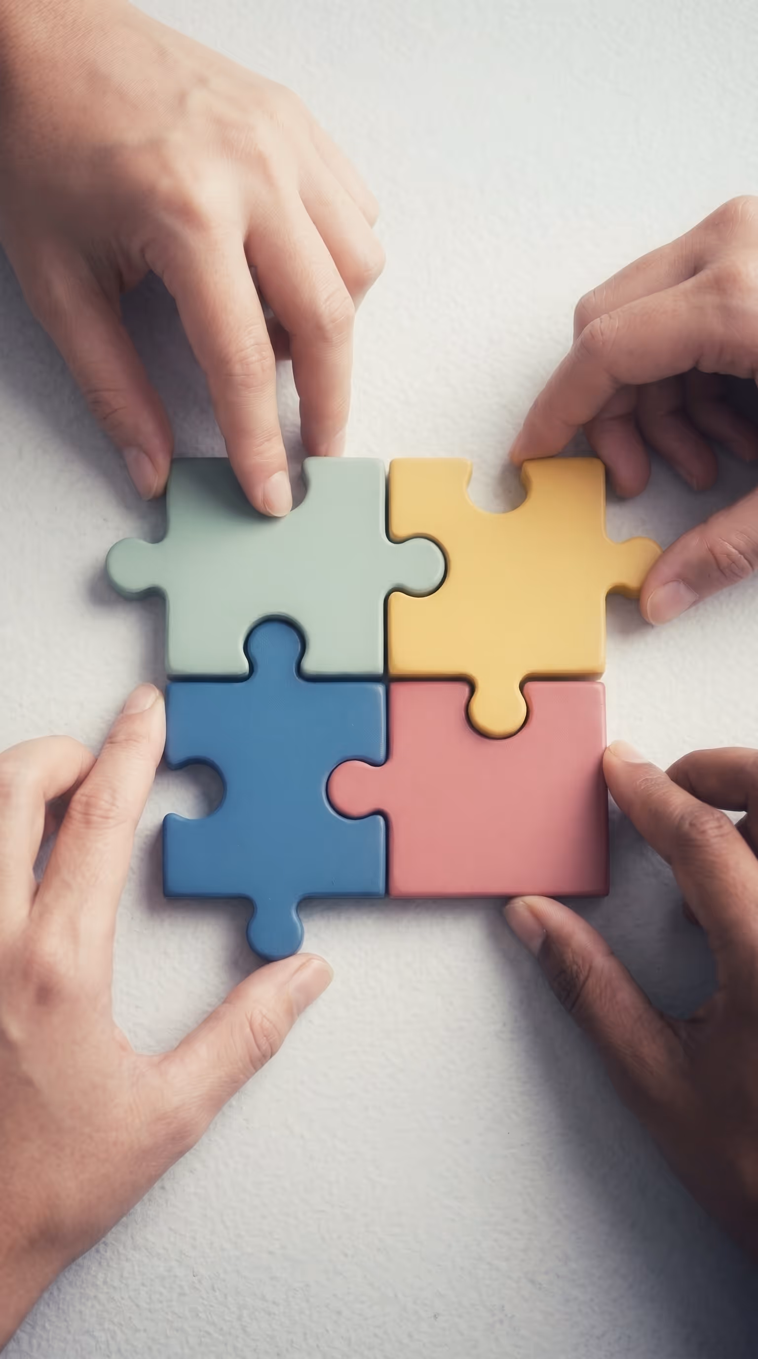 Multiple hands assembling colorful puzzle pieces, representing how Matidor connected Surge Energy's teams, vendors, and site data into one coordinated asset retirement program