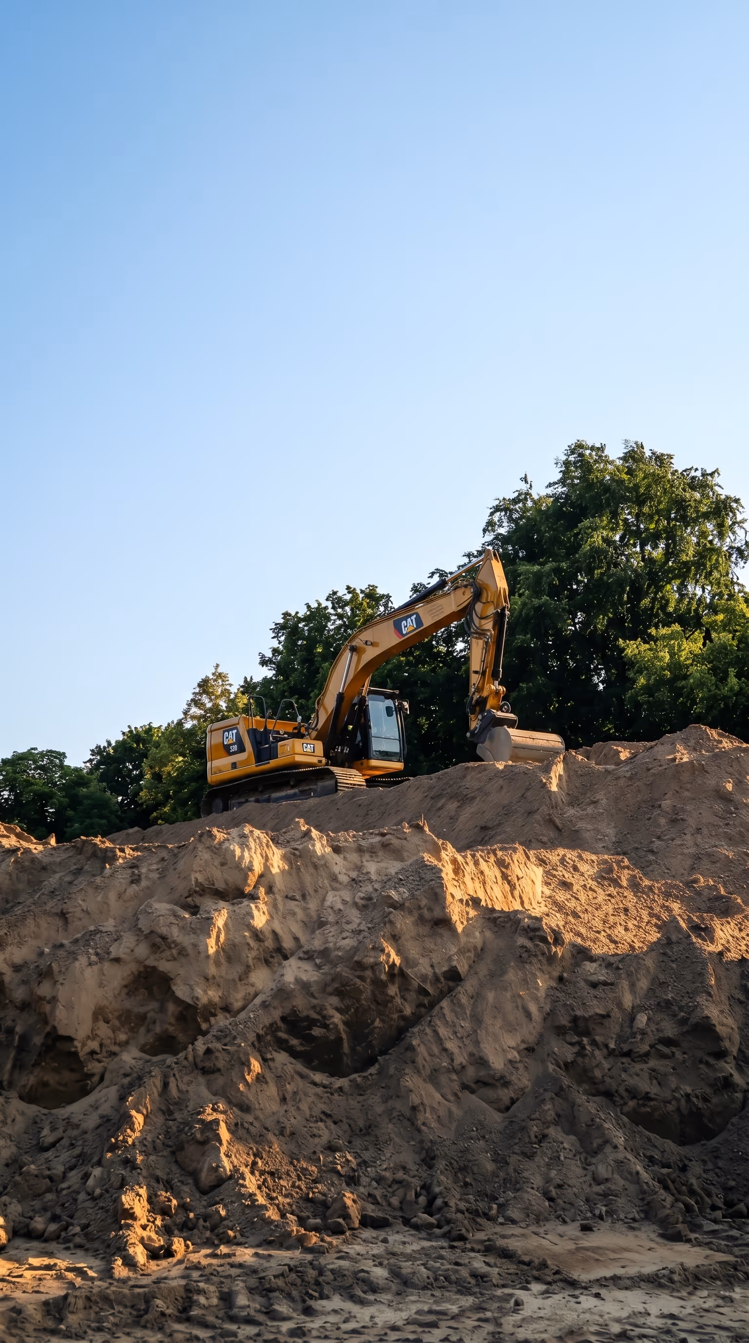 CAT excavator at an active environmental remediation and reclamation field site, representing the type of ground-level work RidgeLine Canada coordinates and plans using Matidor's location intelligence and GIS mapping tools