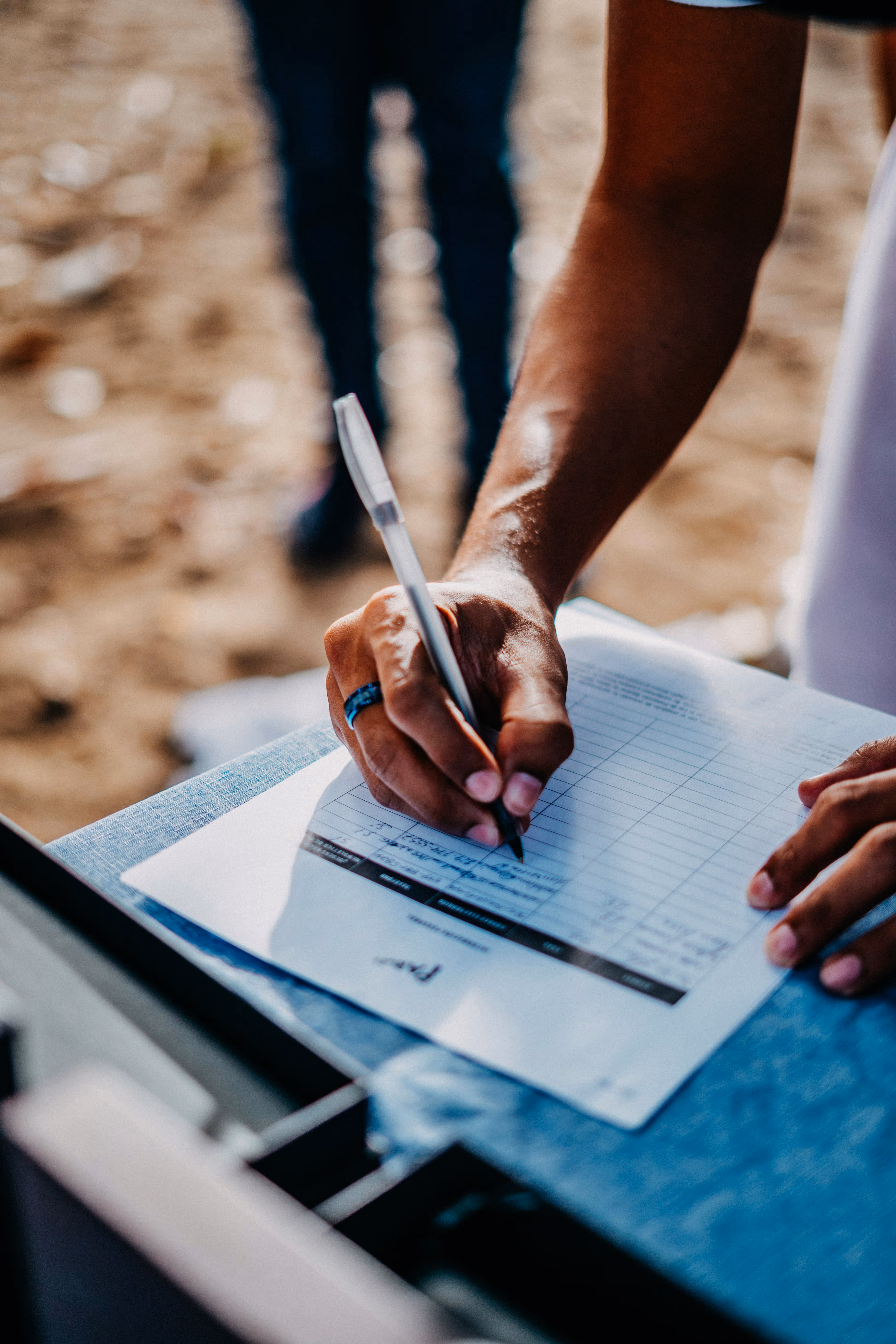 Field staff member filling out a paper log sheet outdoors, illustrating Pease Park Conservancy’s manual park operations workflow before adopting Matidor