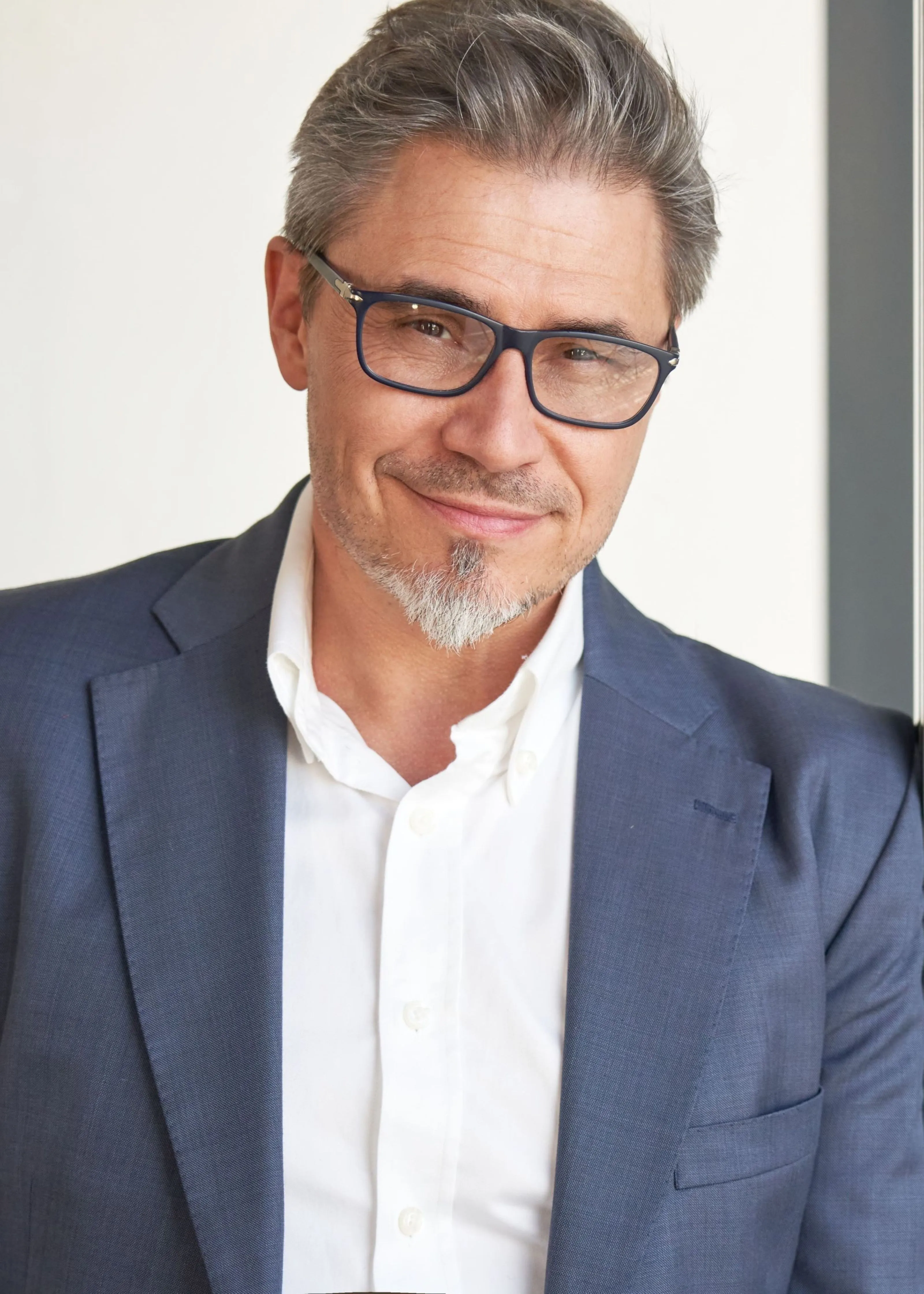 A man smiling leaning on a wall